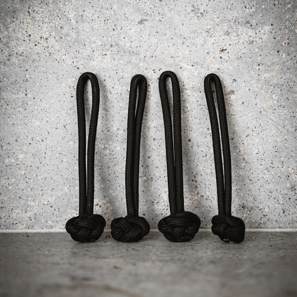 1 set of black ropes leaning on a wall.